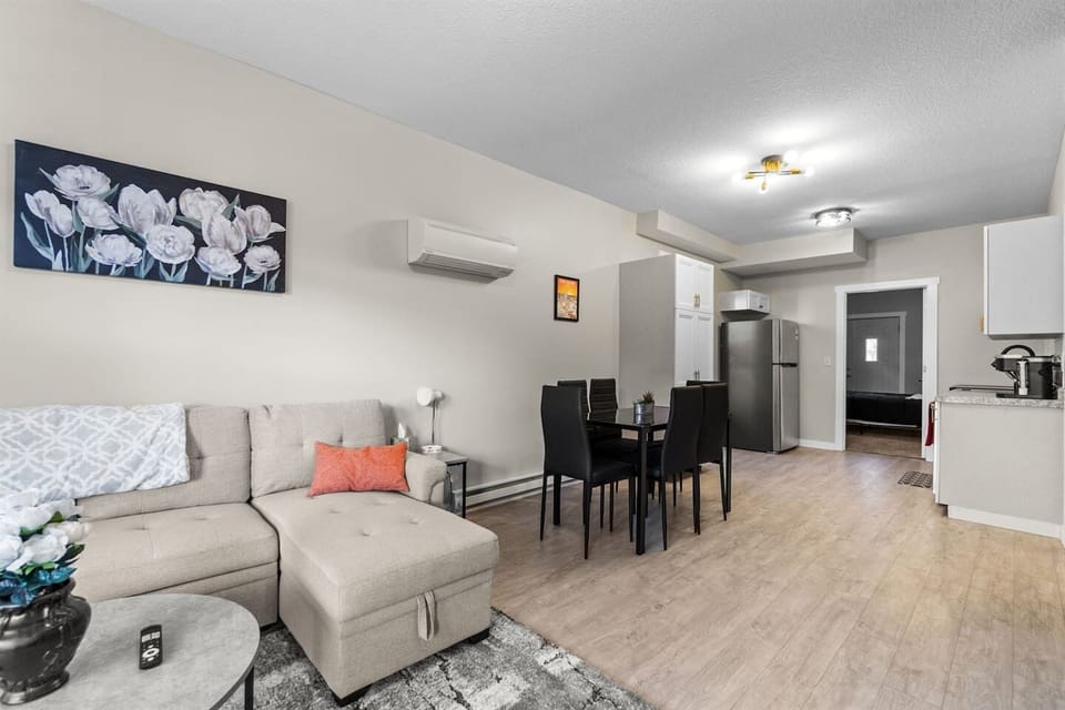 Open-concept living room with a sectional sleeper sofa, leading seamlessly into the dining area and modern kitchen for a spacious, connected feel.