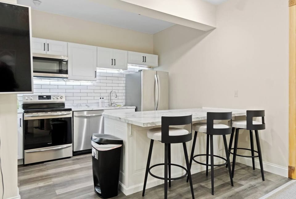 Modern kitchen featuring a sleek countertop with seating for three, complemented by elegant white interiors for a clean and stylish look.