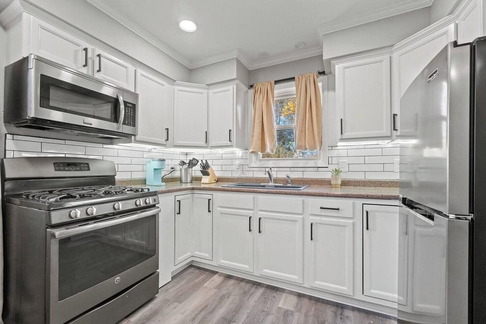 Fully equipped kitchen with a fridge, microwave, gas stove with oven, knife set, and all the essential cookware for your convenience.