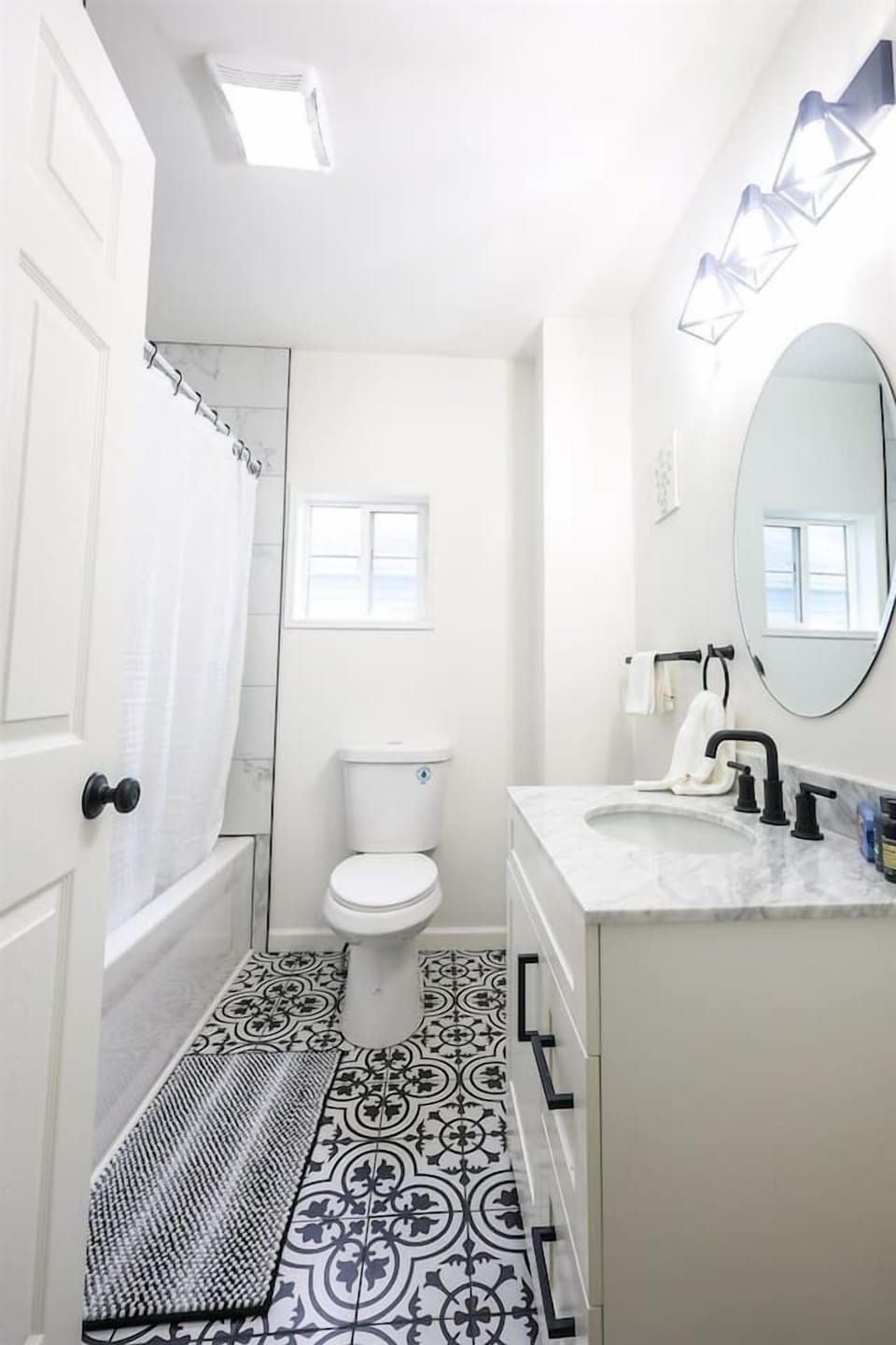 This full bathroom features a shower tub and minimalist design, offering a clean, serene space for relaxation and comfort.

