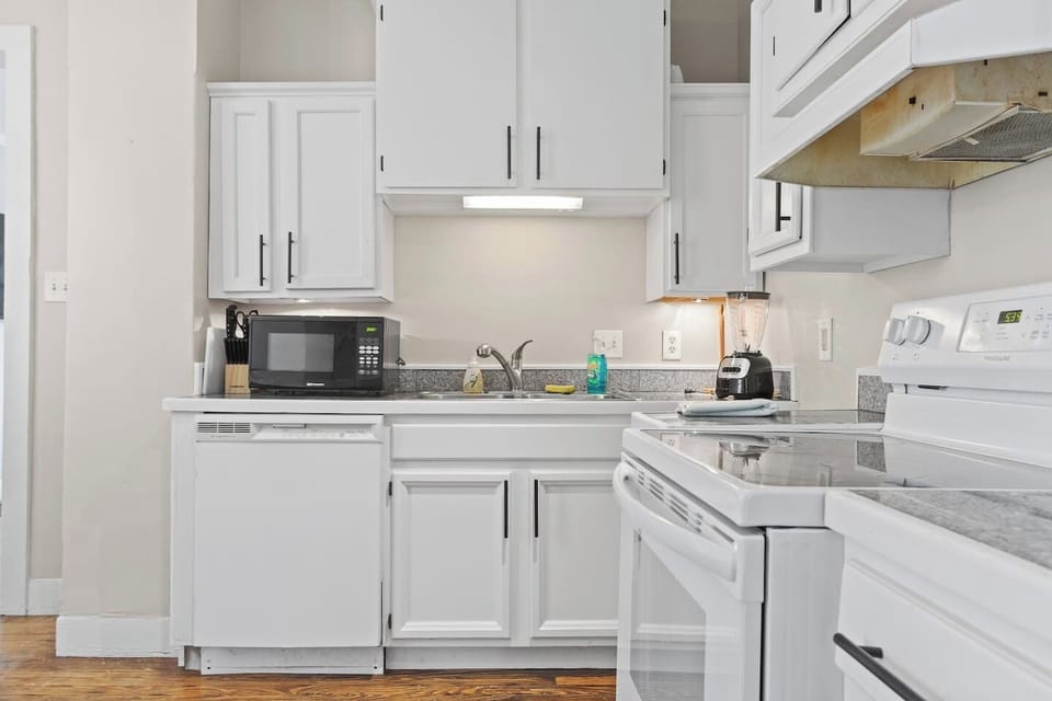Well-equipped kitchen featuring a microwave, stove with oven, and a blender, providing everything you need to prepare meals.