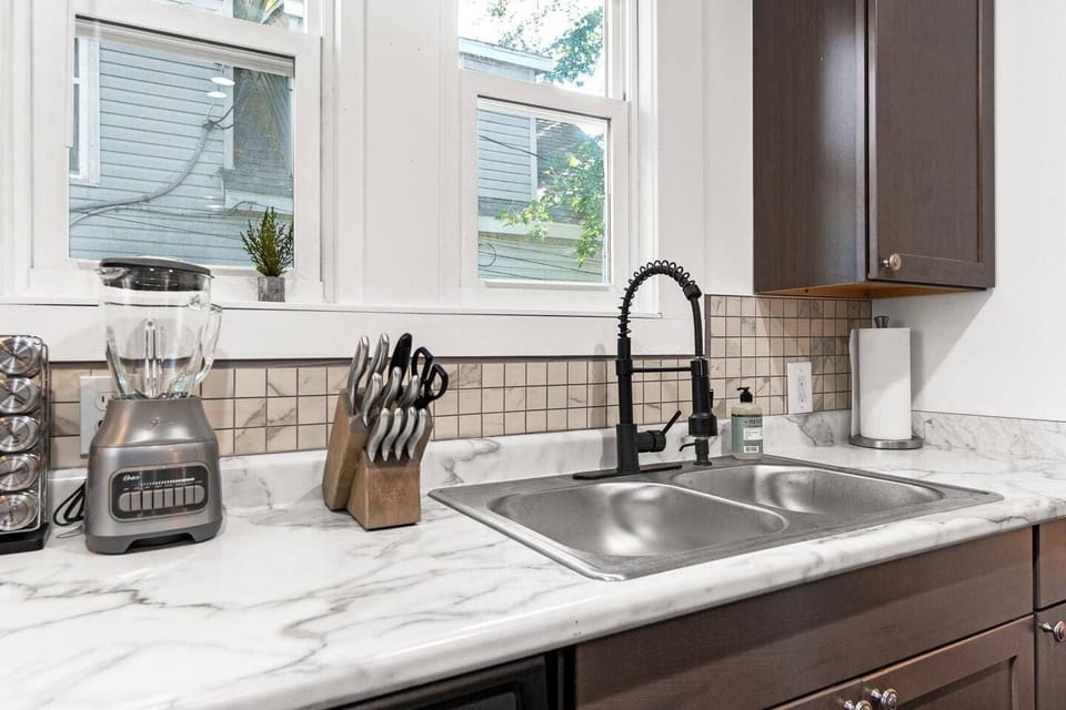 A sleek and fully equipped kitchen counter featuring a high-quality blender, an array of spices, sharp knives for all your culinary needs, and convenient paper towels. Perfect for whipping up your favorite recipes or enjoying a quick snack!