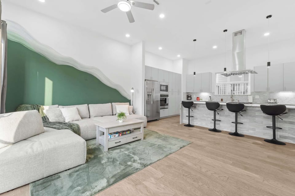 Spacious living area w/ wide layout, green feature wall & seating made for unwinding.