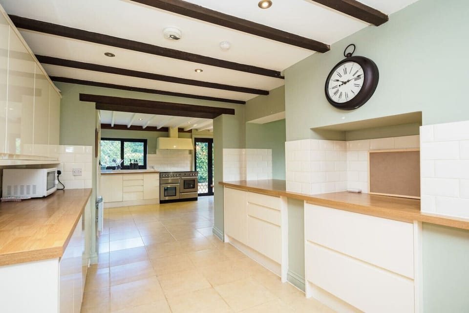 Spacious kitchen corridor with beamed ceilings, oak worktops, and the range cooker ahead.