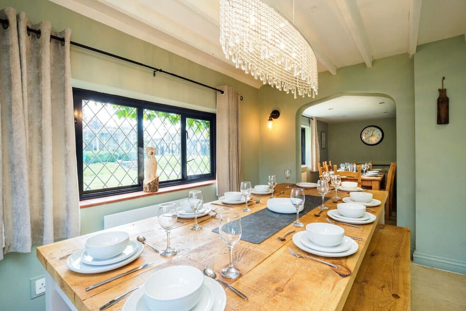 The long rustic dining table is laid for a feast beneath a sparkling crystal chandelier.