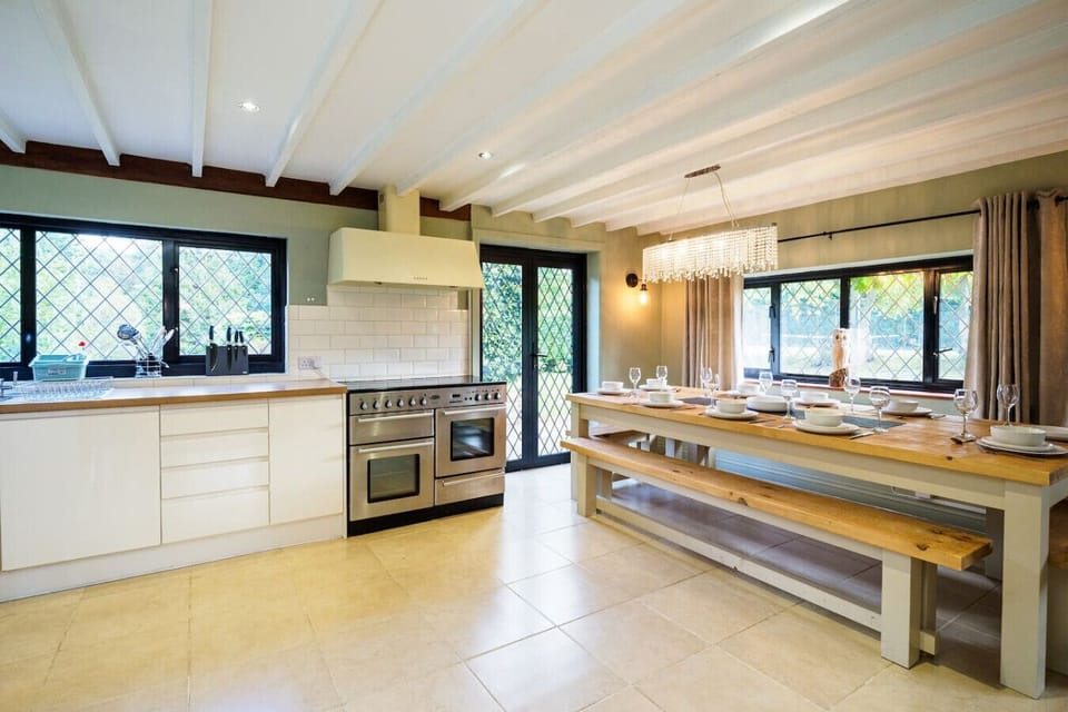 Open kitchen-diner with a range cooker, farmhouse bench table, and garden light flooding in.