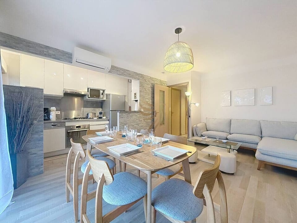 Pièce de vie moderne et lumineuse avec cuisine équipée ouverte et espace repas convivial.