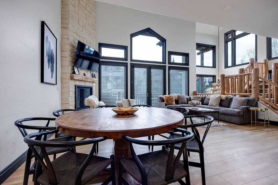 Your open-concept space flows beautifully from dining to living area, with soaring windows flooding warm wood and modern furnishings with natural light.