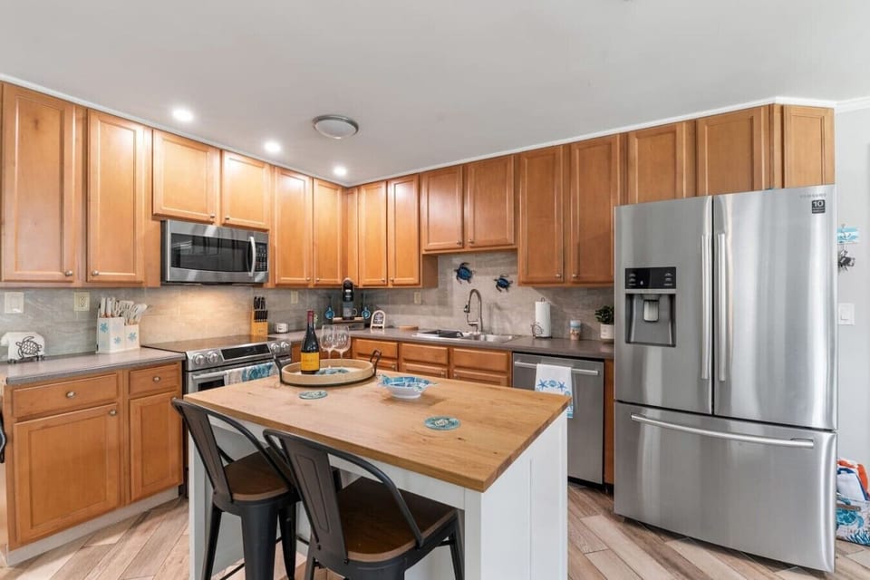 Fully equipped kitchen at Sun Oasis with stainless appliances, warm wood cabinetry, butcher-block island, and playful sea-turtle accents — everything a group needs to cook in style.