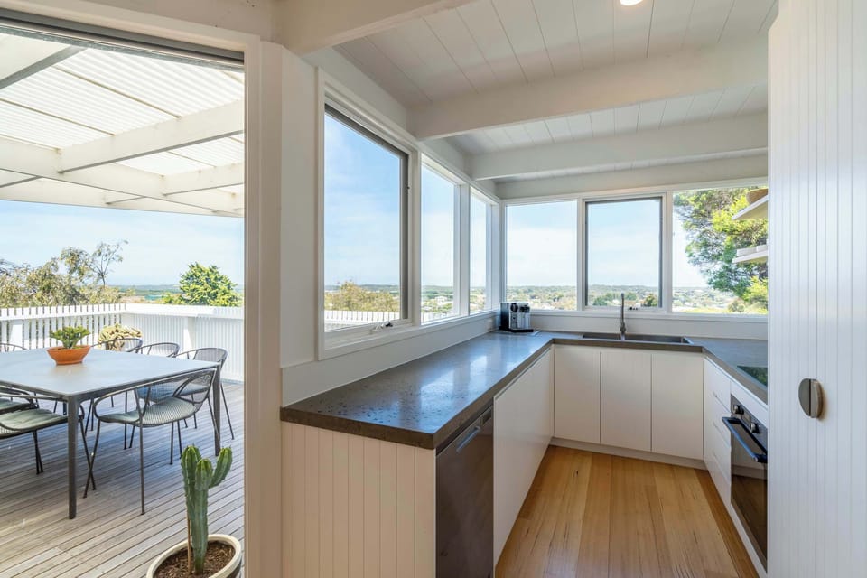 Seamless indoor-outdoor living connects the open plan living, dining, and kitchen area to the generous balcony