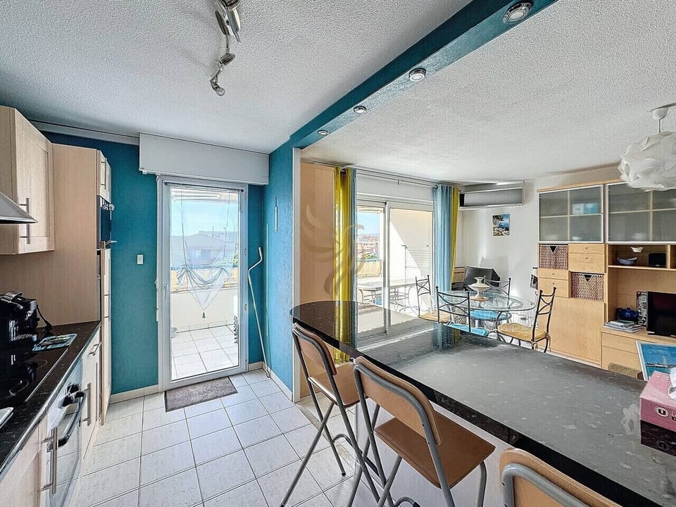 cuisine équipée avec comptoir et chaises hautes pour déjeuner et accès terrasse avec table et chaises