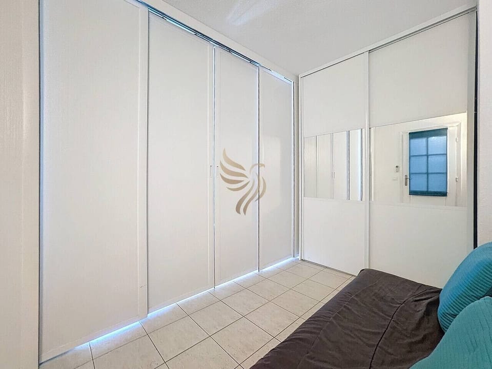L`espace intègre un grand placard avec miroir, idéal pour maximiser le rangement. Imaginez cette pièce transformée pour héberger un invité grâce au canapé convertible situé discrètement d`un côté de la pièce.