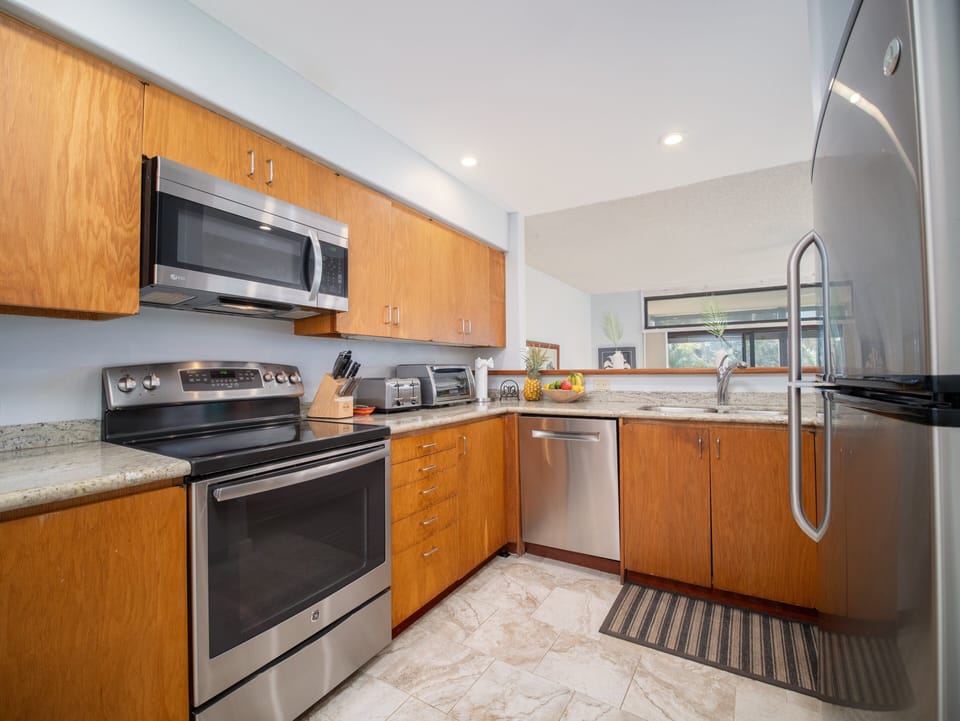 Fully equipped kitchen with stainless steel appliances, perfect for preparing meals after a day exploring nearby beaches and attractions.