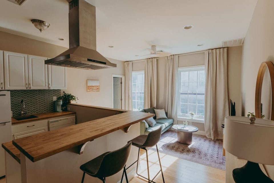 Cozy open-concept kitchen and living space with cabinets, wooden counter and stools
