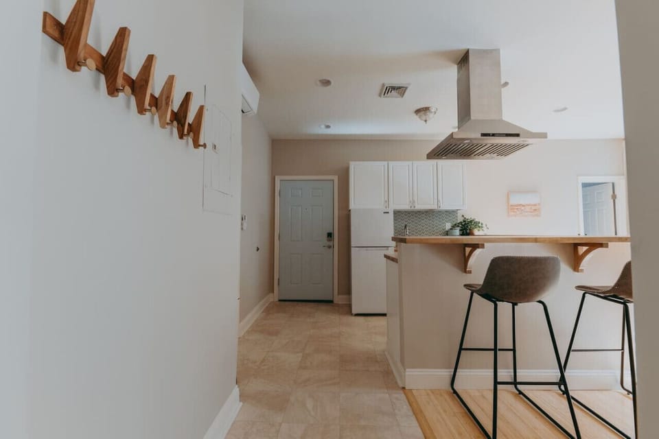 Modern kitchen with a bar counter, barstools, a fridge, and white cabinets