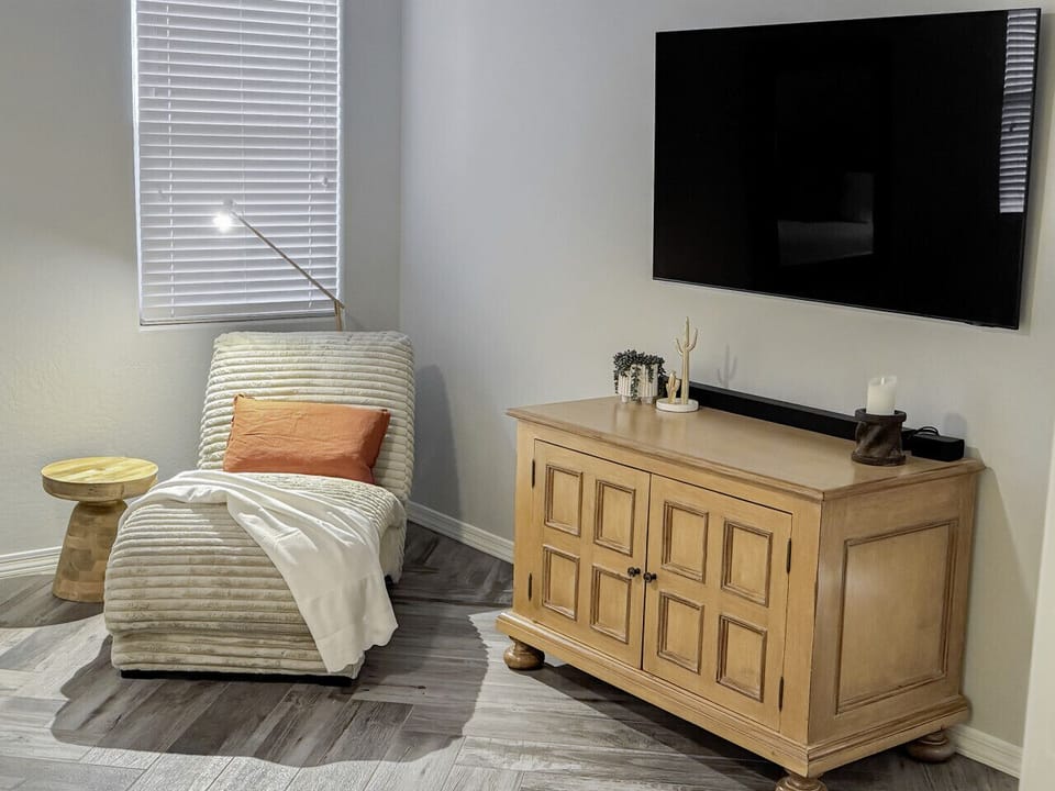 The plush lounge chair sits comfortably next to a 65-inch smart TV, offering a cozy and inviting space for relaxation.