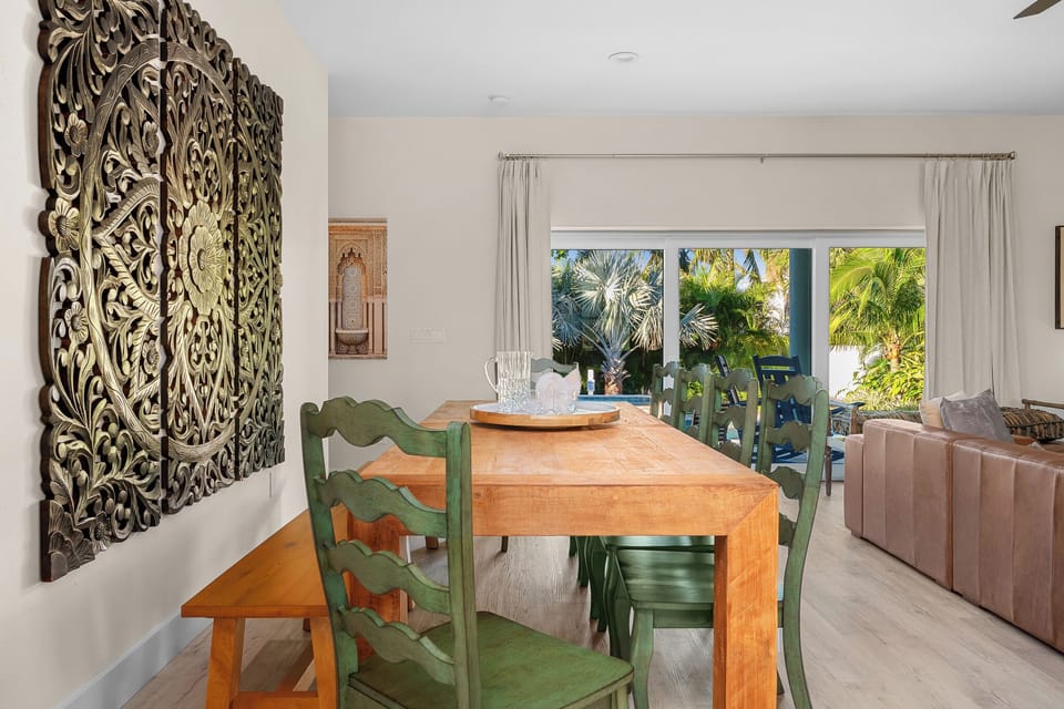 Elegant dining area with a large wooden table and tropical views, perfect for gatherings!