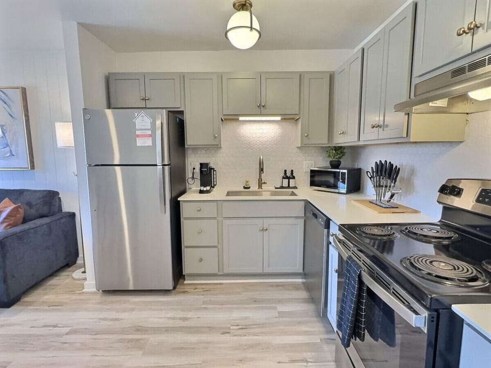 Modern kitchen with sleek stainless steel appliances and neatly arranged utensils, perfect for effortless cooking during your short-term rental stay.