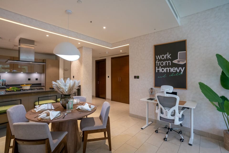 Dining table set for four, kitchen with stove, and a work desk with a comfy chair