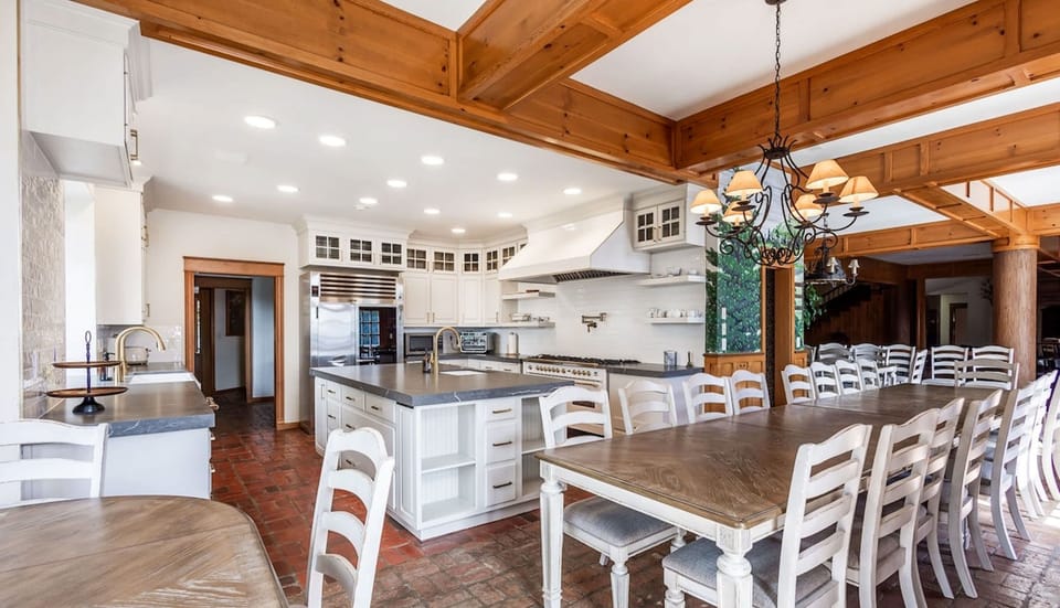 Guests can cook and gather in the main kitchen, equipped for large groups, before enjoying meals in the grand dining room with seating for 35, where rustic elegance meets panoramic outdoor views.