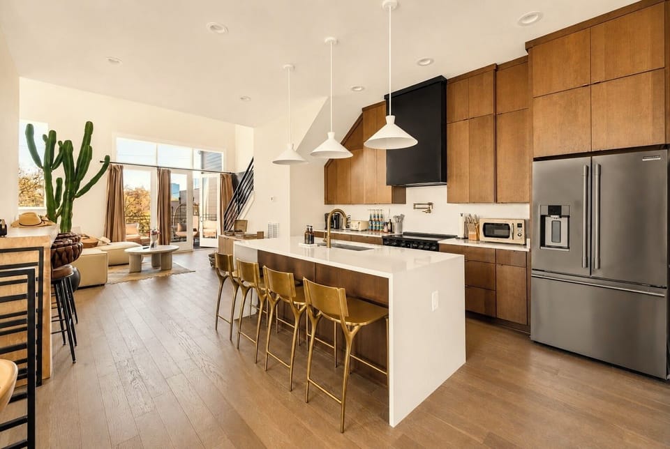 Bright modern kitchen with waterfall island, bar seating, and balcony access.