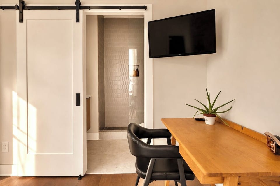 Modern suite workspace with TV and sleek ensuite walk-in shower.