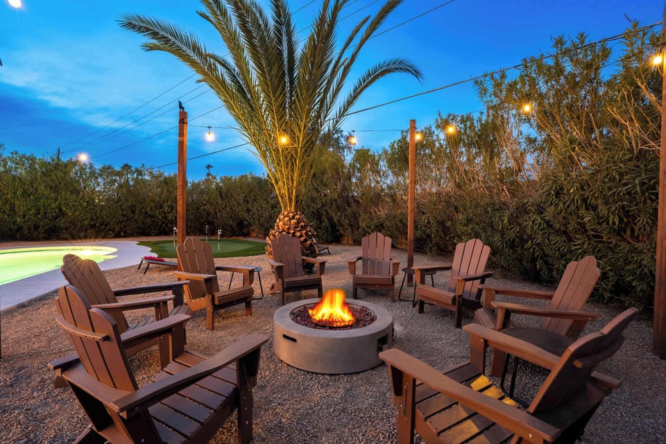 Relax by the pool with ample seating around the firepit, all illuminated by cozy string lights for the perfect evening atmosphere.