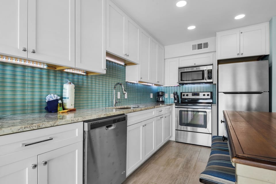 Your modern kitchen awaits with granite counters, turquoise backsplash, and full stainless appliances for memorable vacation meals.
