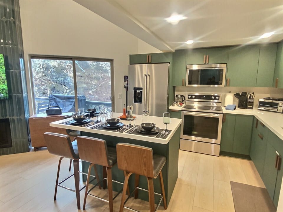 Your modern kitchen features sleek green cabinets, stainless steel appliances, and a spacious island where you can gather for meals and conversation.