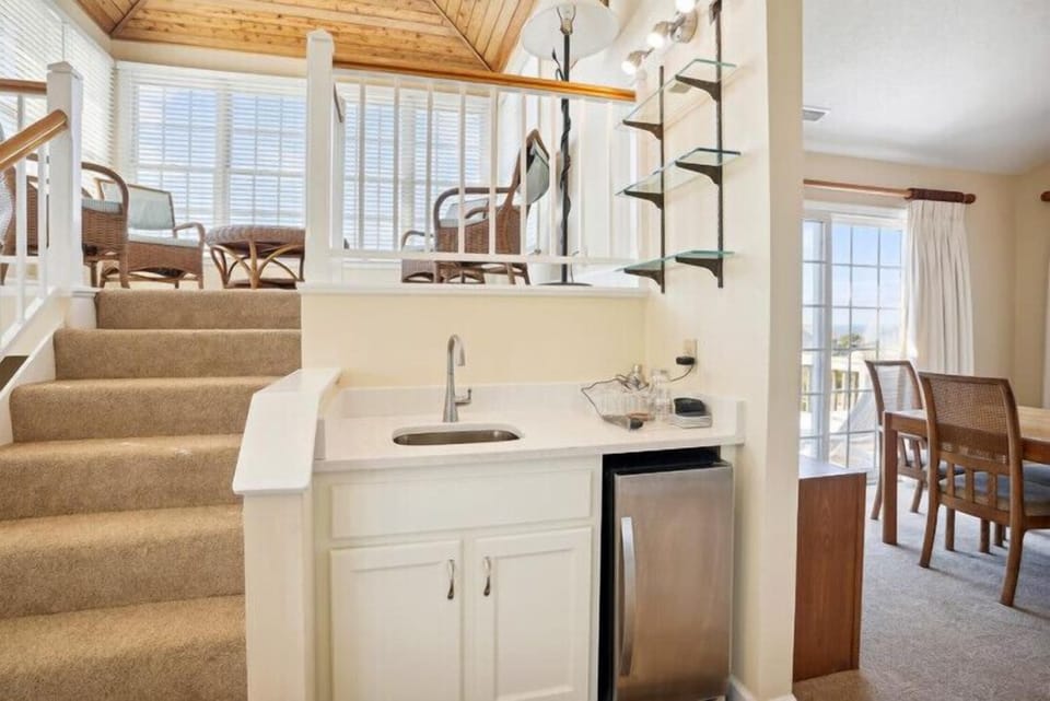 Bright open layout with a wet bar, cozy loft seating area above, and dining space with balcony access—perfect for entertaining or unwinding after a day of adventure.