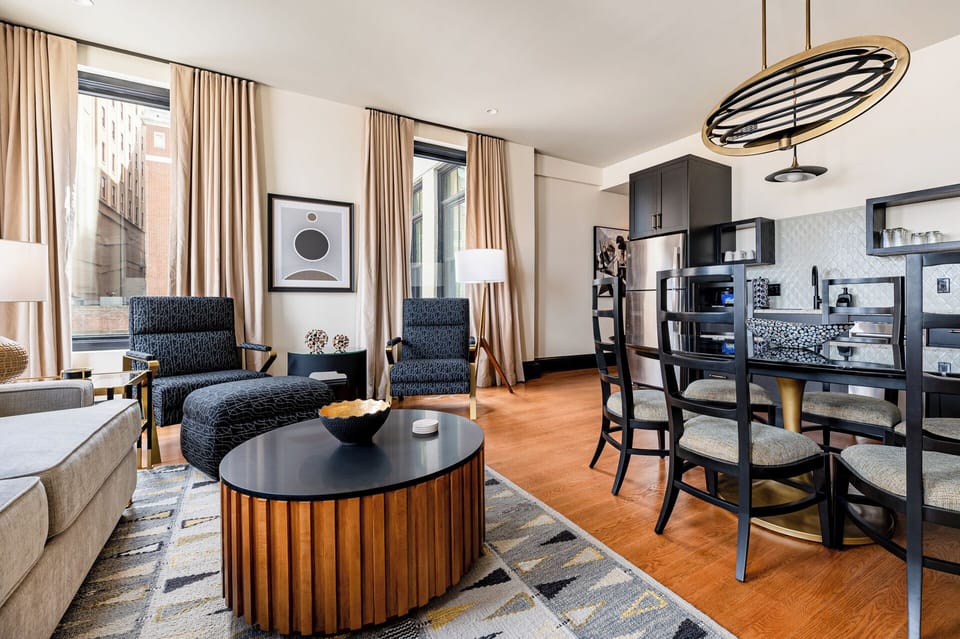 Living room 1 - Bright and open living space with a modern design, featuring warm tones and decor. The tall windows fill the room with natural light, creating a welcoming and comfortable atmosphere.