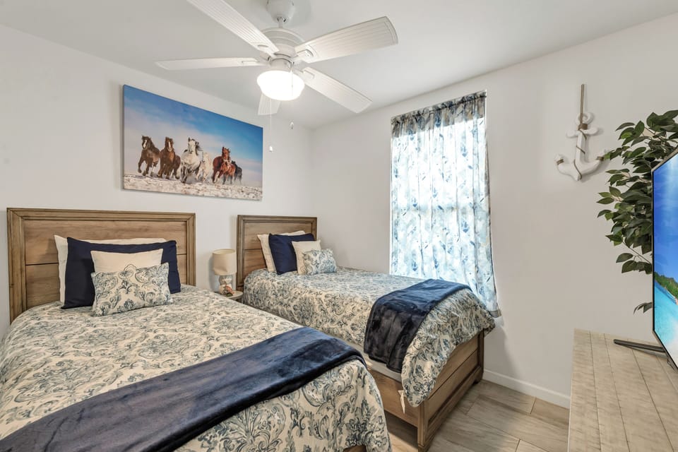 Rest peacefully in your bright twin bedroom with comfortable beds, ceiling fan, and charming horse artwork creating a welcoming retreat.