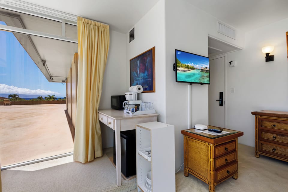 Your room blends comfort and practicality with a TV, coffee setup, mini-fridge, and charming tropical furnishings—plus easy access to your private outdoor terrace.