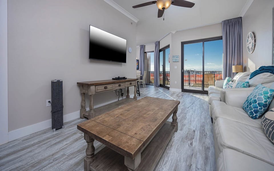 Relax in the inviting living area with a large TV, sofa with queen sleeper, and stunning beachfront balcony views