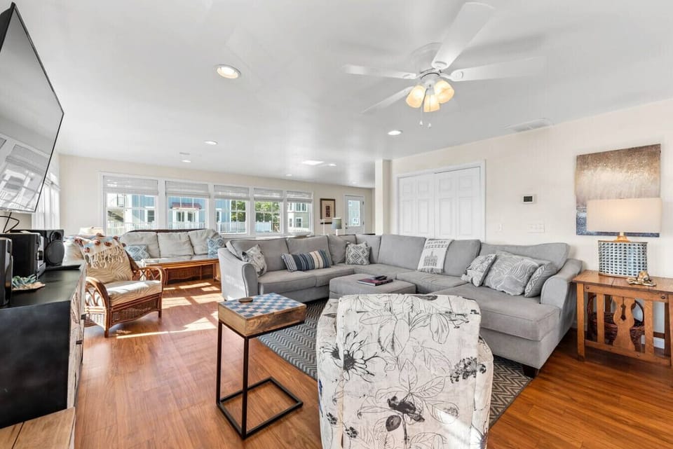 Main living area of game room contains plenty of sitting, 65 inch wall mounted TV with full cable chanels and smart TV apps, as well as music player/sound bar.   checkers, card games, bumper pool, shuffle board and arcade system and access to deck.