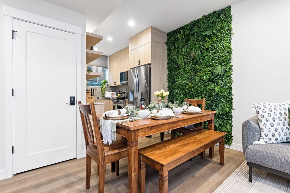 Bright dining space—wood tones & a lush green wall for a fresh, natural vibe.