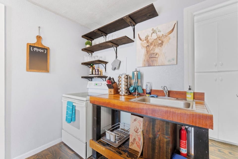 Modern stove with open shelving above for easy access to kitchen essentials, and a sink stocked with supplies for your convenience.