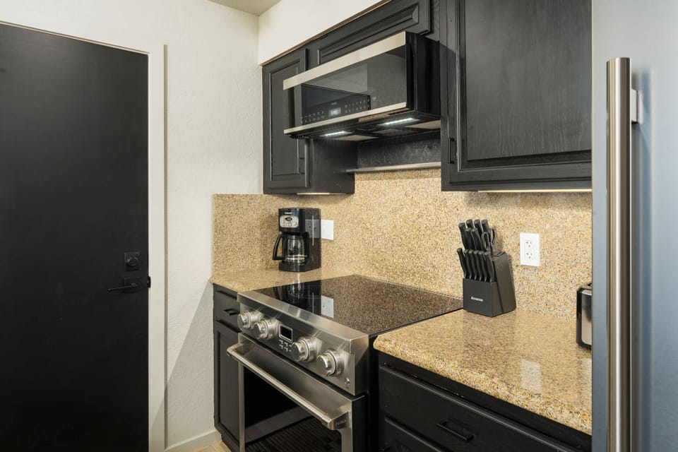 Your fully equipped kitchen features sleek dark cabinetry, granite countertops, stainless steel appliances, and everything you need to cook and entertain during your stay.