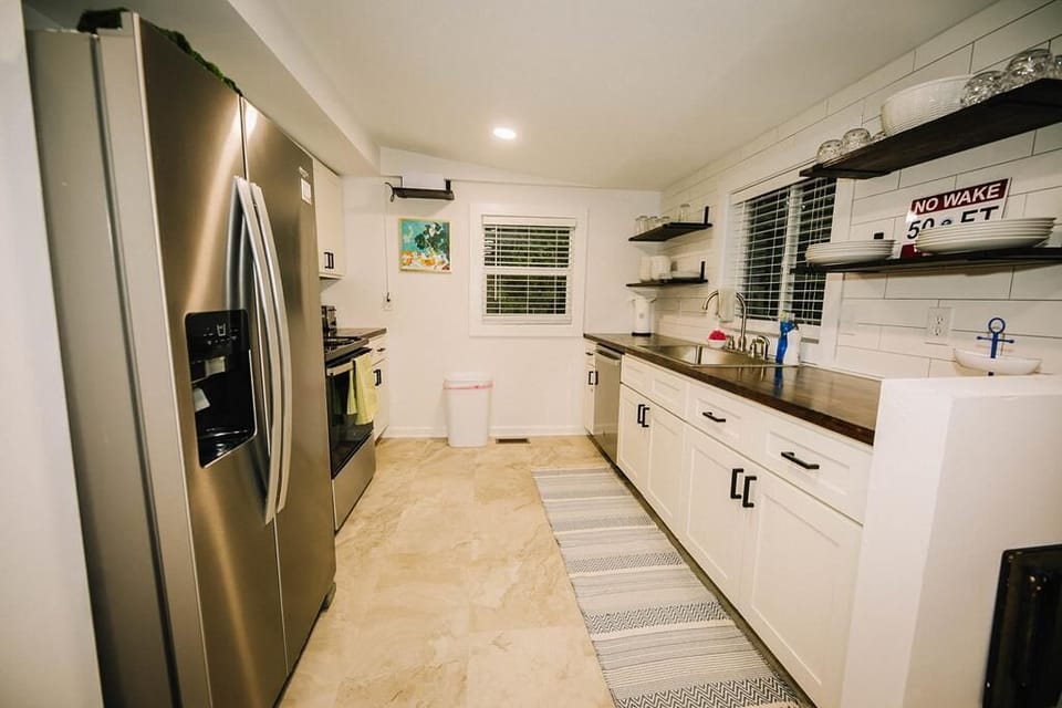 Modern kitchen with stainless steel appliances, open shelving, and a farmhouse-style design.