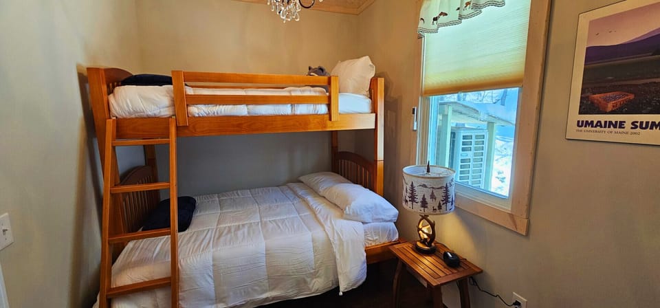 Bunk bedroom featuring a twin-over-queen bunk bed, cozy lighting, and rustic cabin décor, perfect for families or groups.