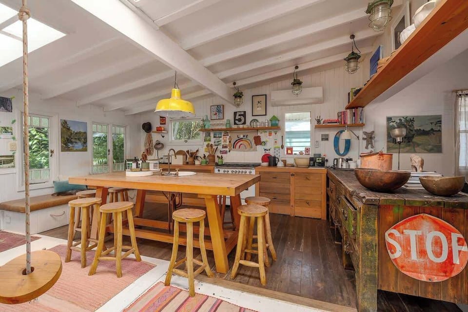 A character-filled country kitchen with timber floors, breakfast bar seating and playful styling including a swing; perfect for relaxed meals during your Bangalow village getaway.