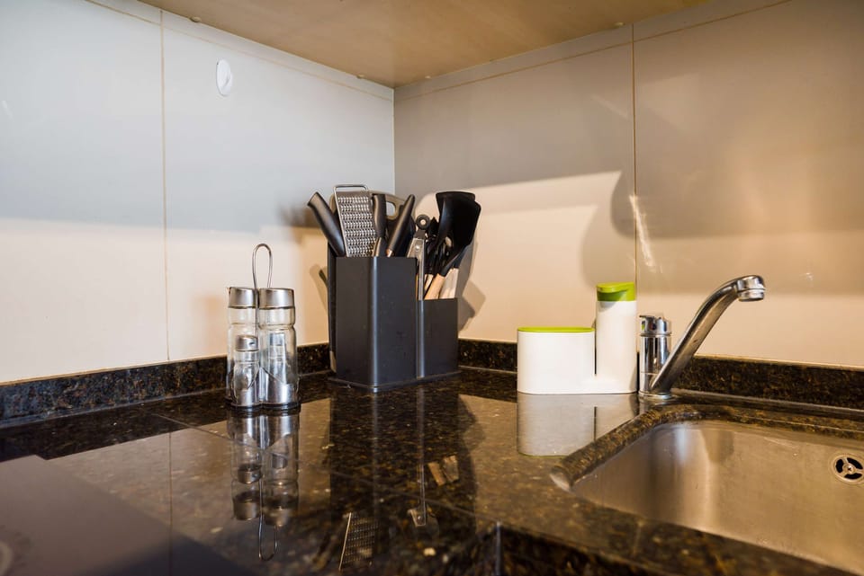 Modern kitchen corner with sleek granite countertops and essential utensils for a comfortable stay.