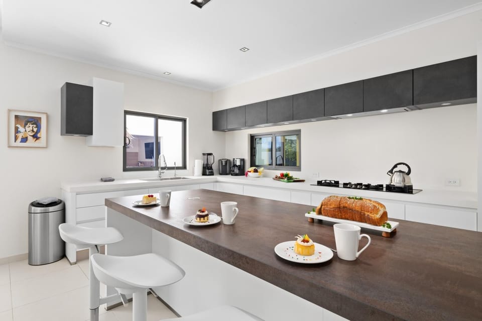 Step into the modern kitchen featuring a sleek kitchen island with 5 stools, perfect for casual meals or socializing while you cook. A stylish and functional space to gather and create delicious memories.