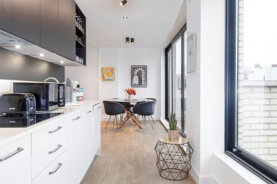 Open-plan living room and kitchen with a TV area and access to a private balcony with chairs.