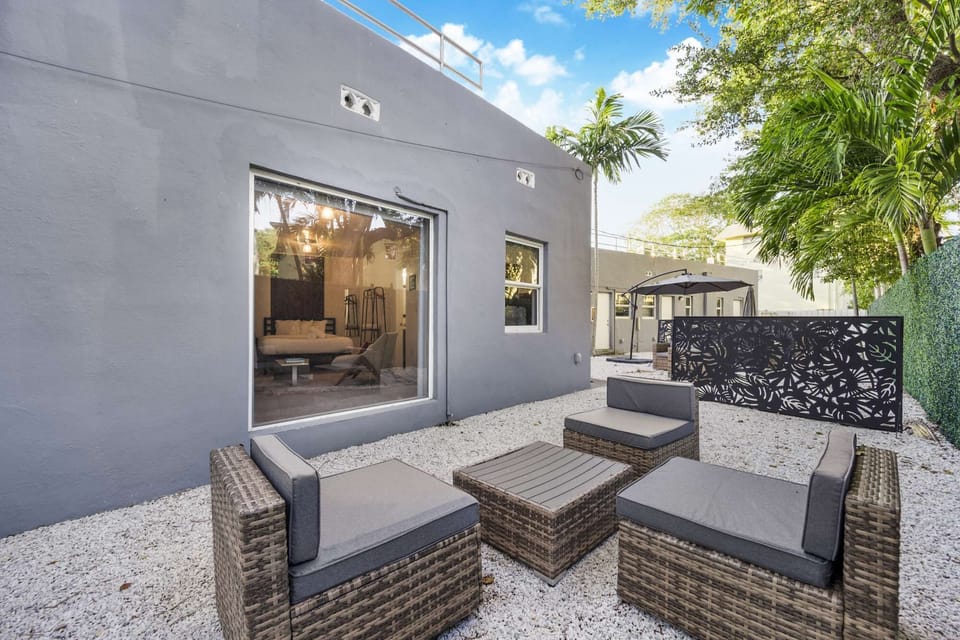 Patio with wicker chairs, tables, umbrella, and paved ground