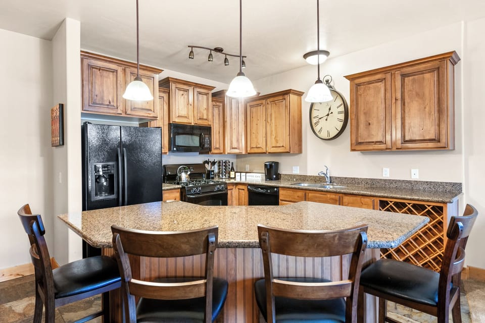 Prepare meals with ease in the fully equipped kitchen featuring stainless steel appliances, granite countertops, and a breakfast bar with seating for four.