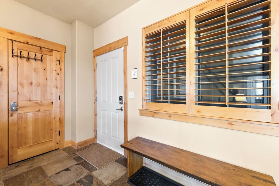 Convenient entryway with a bench, coat hooks, and plenty of space to store jackets, boots, and ski gear after a day exploring the mountains.