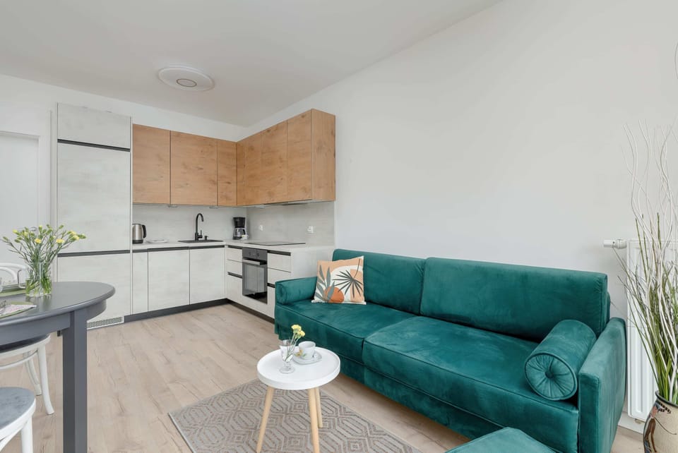 A modern living room with a green sofa and TV cabinet. The neutral tones are accented by soft lighting.