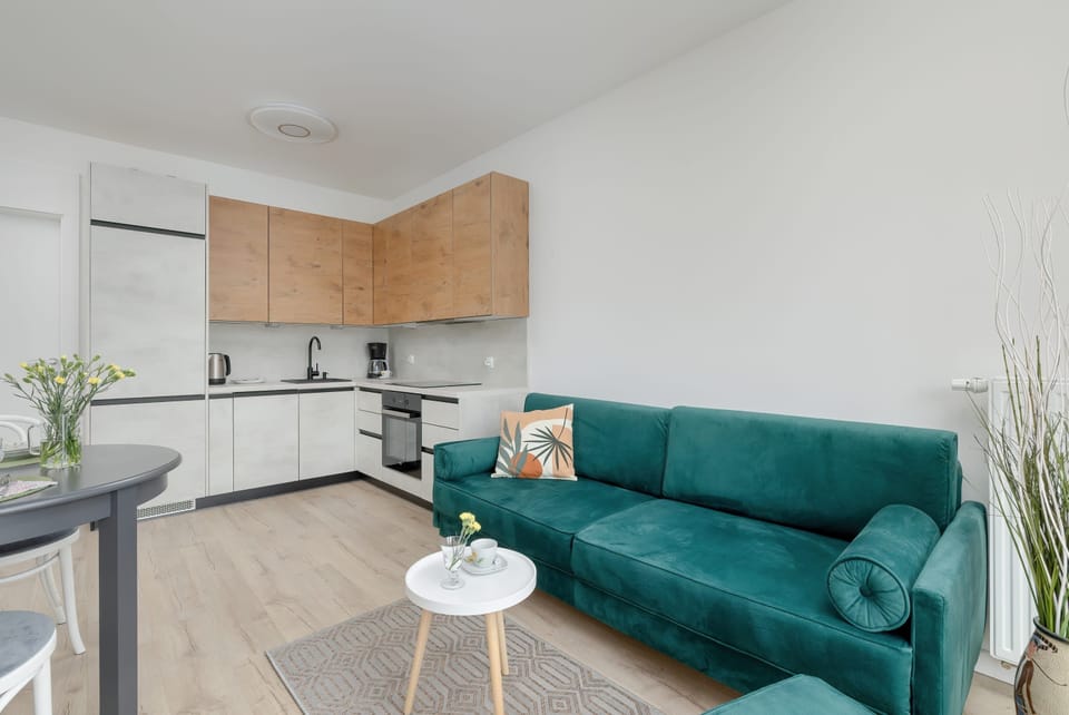 A modern living room with a green sofa and TV cabinet. The neutral tones are accented by soft lighting.