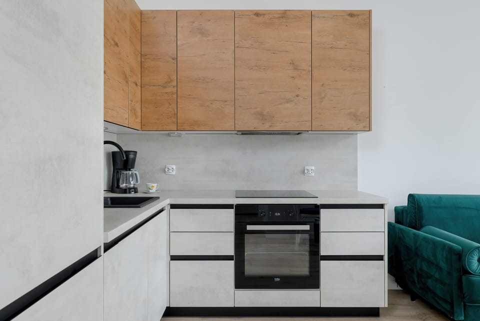 A stylish kitchen with a sleek black oven and ceramic hob. The light walls and wooden cabinets create a warm contrast.